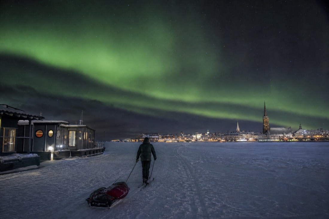 Person on skis crossing the frozen bay from the houseboats toward Old Town pulling a small sled of supplies