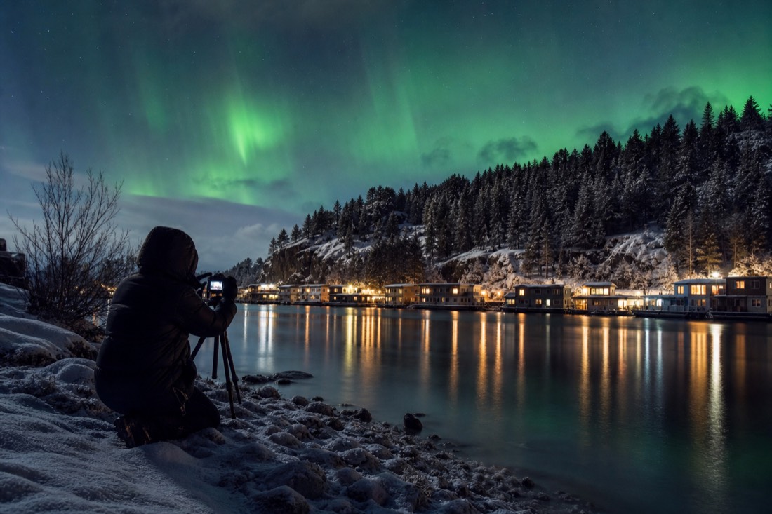 Photographer on the Old Town shoreline framing the distant houseboats across the water in evening light