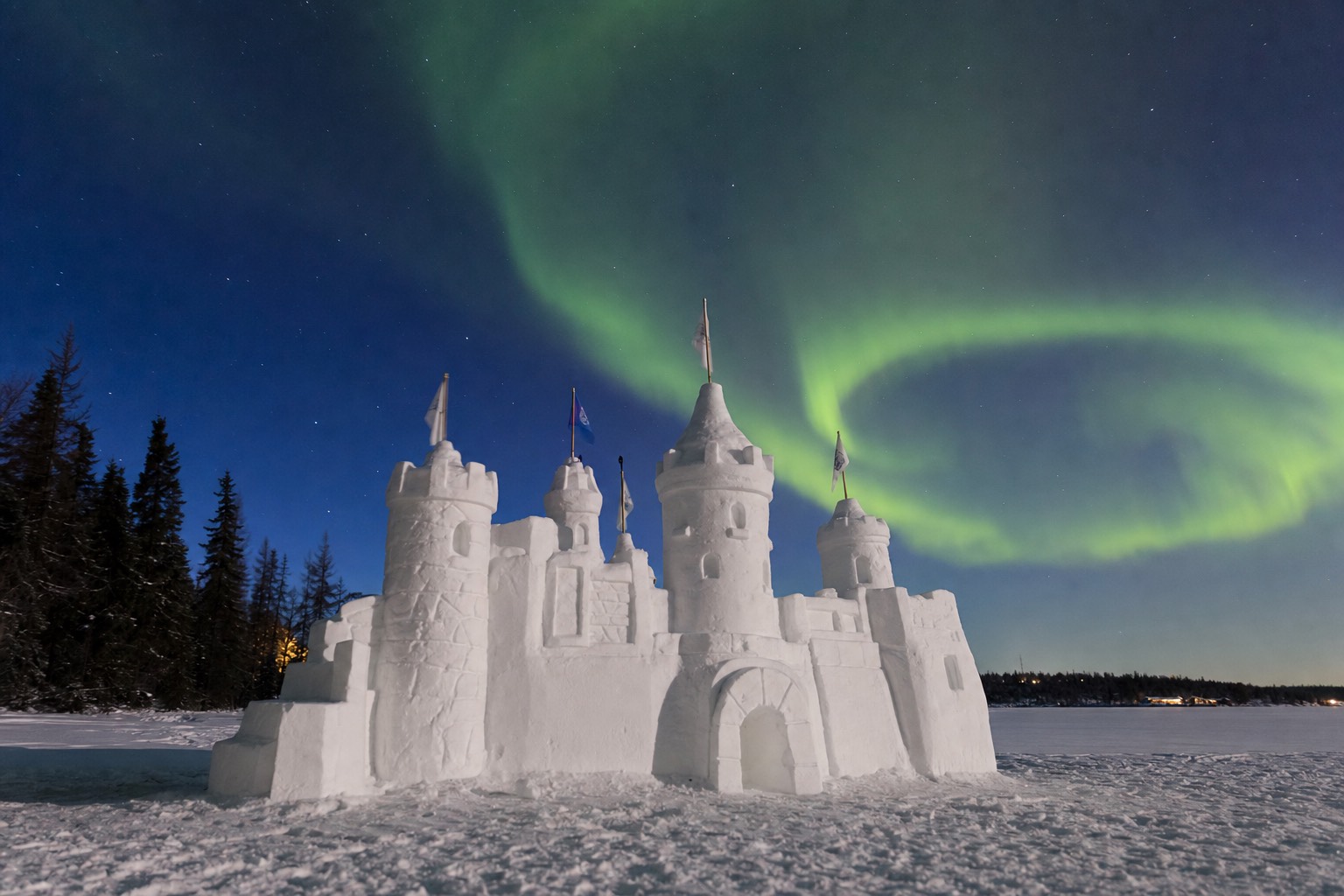 Carved snow castle with towers and flags standing on the frozen surface of Yellowknife Bay in March sunshine