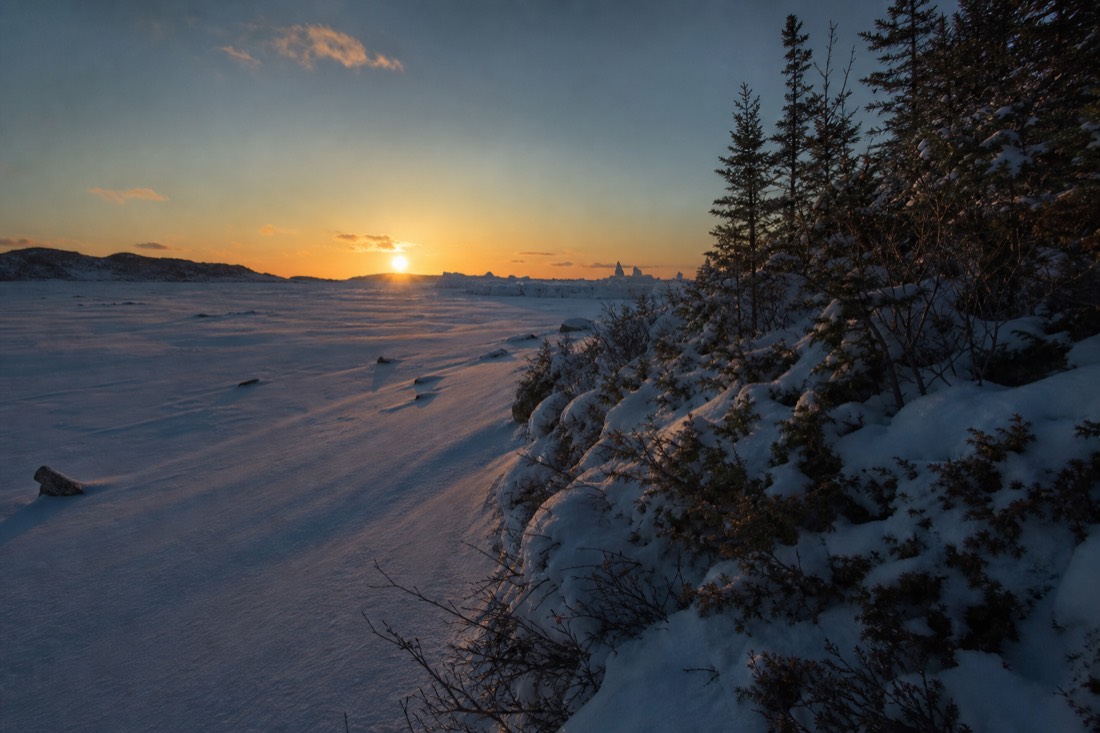 Late afternoon March sun over the frozen bay with long blue shadows and the snow castle in the distance