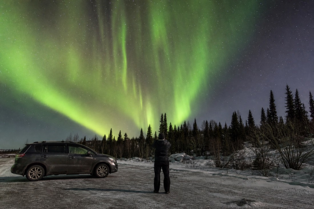 Tour guide checking the night sky from a dark highway pullout east of Yellowknife