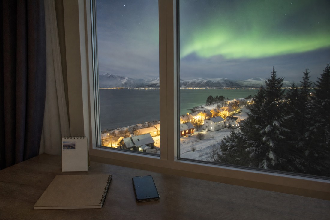 Notebook, calendar and phone on a hotel desk beside a window looking out on a snowy northern town
