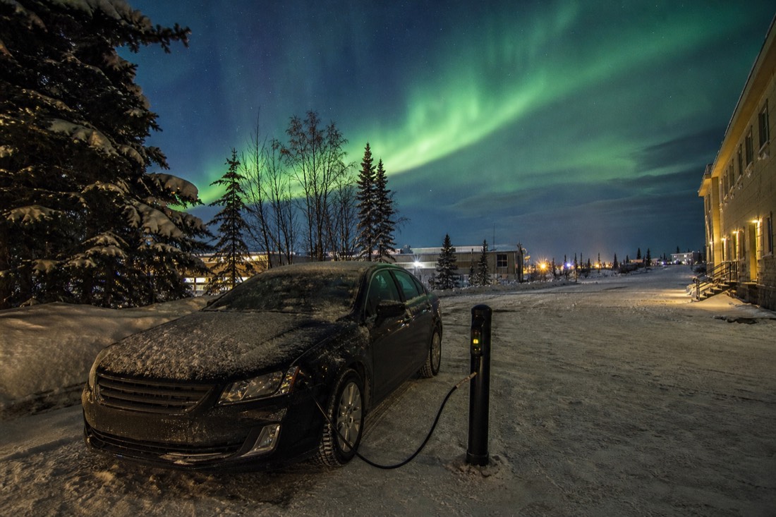 Winterised rental car plugged into a block heater post outside a Yellowknife hotel on a dark winter afternoon