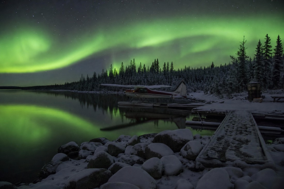 Small floatplane moored near a remote fishing lodge dock on a calm East Arm bay of Great Slave Lake