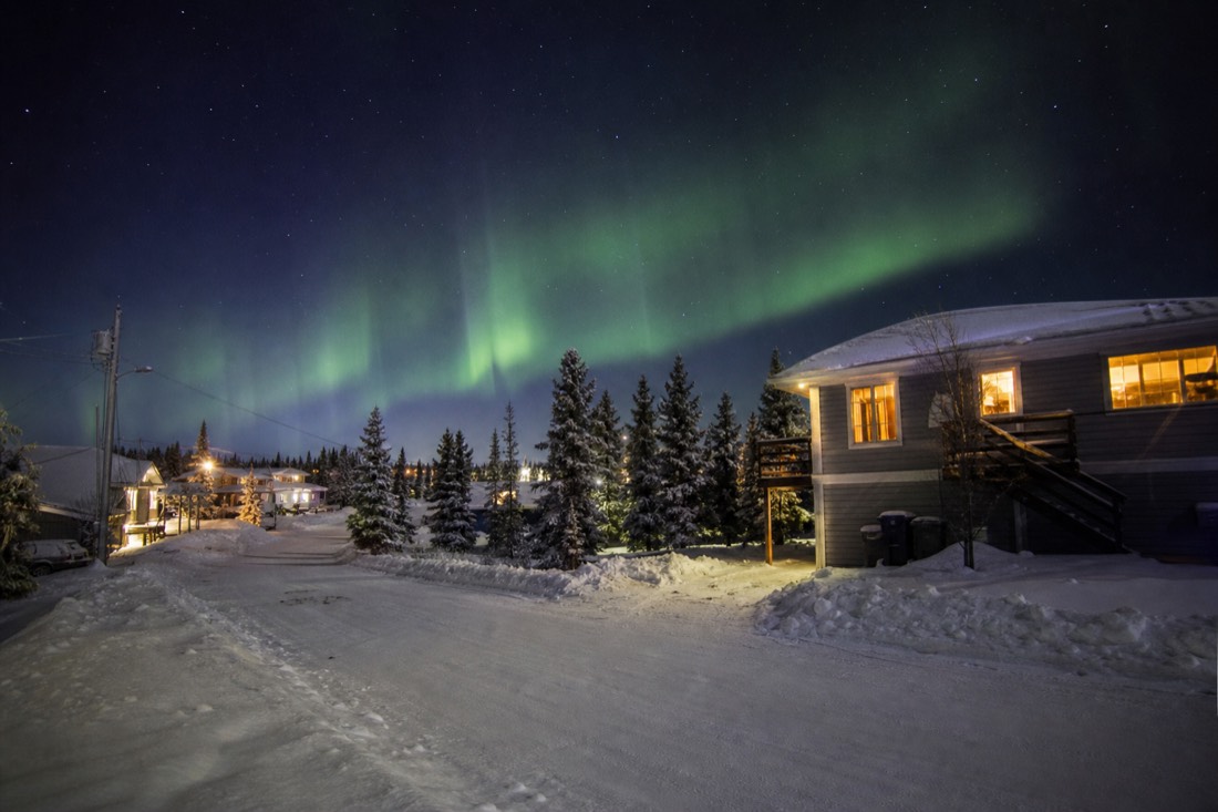 Quiet snow-covered residential street in Yellowknife with warm house lights and a clear evening sky