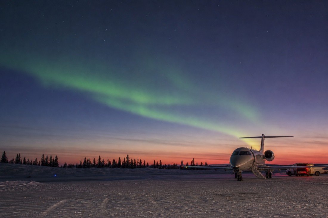Small jet on the snowy apron of Yellowknife airport at dusk with pink twilight on the horizon
