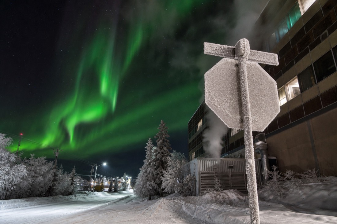 Frost-covered street sign and steaming building vents on a downtown Yellowknife street in deep winter