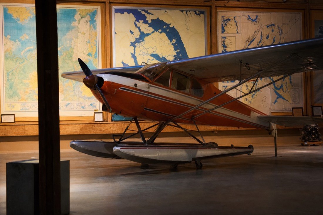 Vintage bush plane displayed in a museum aviation gallery with northern maps on the walls
