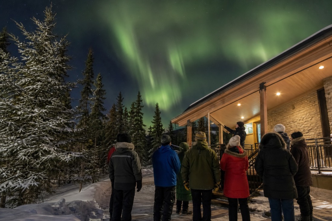 Small tour group listening to a guide outside a museum entrance on a crisp Yellowknife day