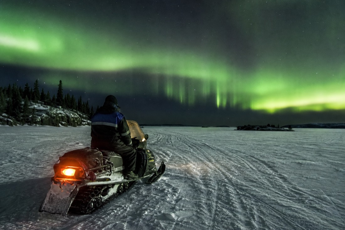 A beginner rider on a snowmobile with heated handlebars crossing wide snow-covered lake ice near Yellowknife