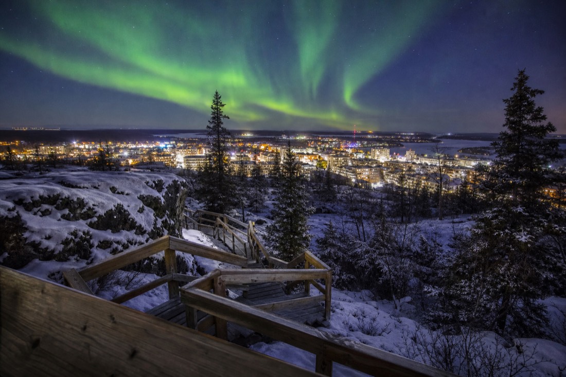 Wooden staircase climbing to the Bush Pilots Monument viewpoint above the rooftops of Old Town Yellowknife