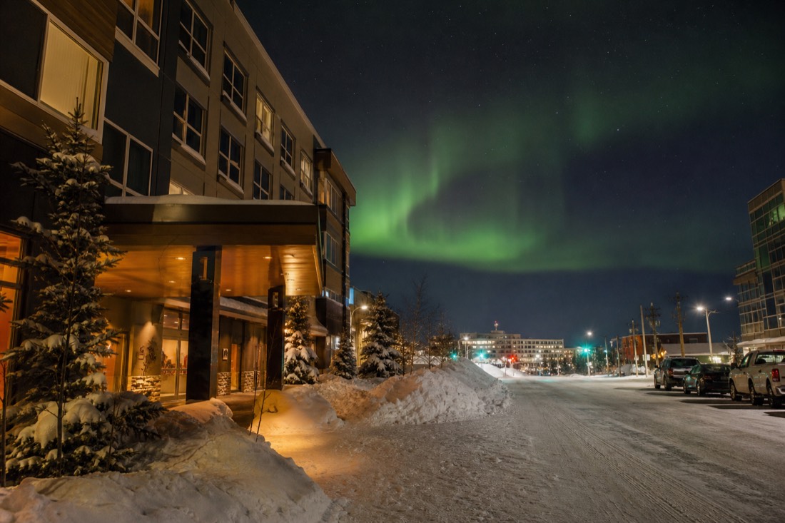 A row of hotel entrances along a snow-banked downtown Yellowknife street with warm lobby light spilling onto the sidewalk