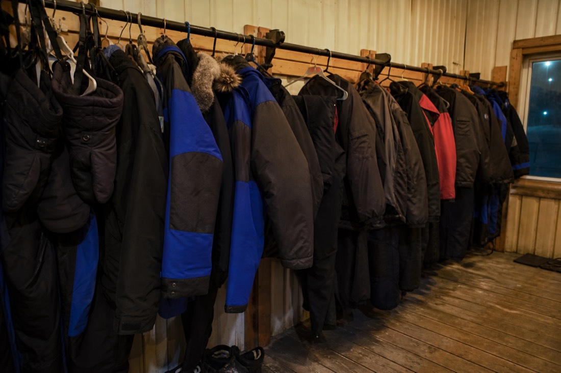 Rack of heavy rental parkas, insulated pants and mitts in a warm Yellowknife outfitting room