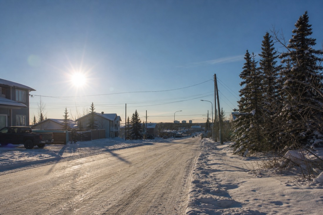 Quiet Yellowknife street in late morning winter light with low sun and long shadows