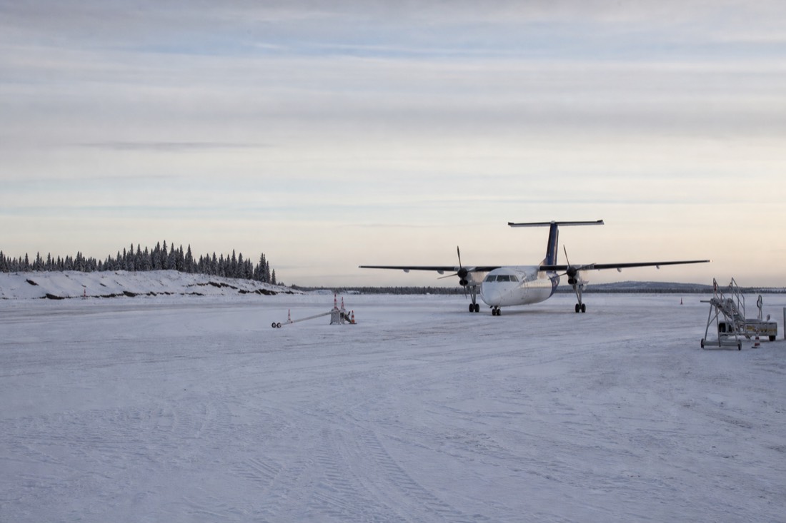 Small airliner on the snowy apron at Yellowknife airport under a pale winter sky