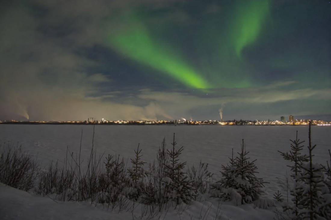 Empty snow-covered open lot on a frozen bay under grey northern sky with a distant town skyline