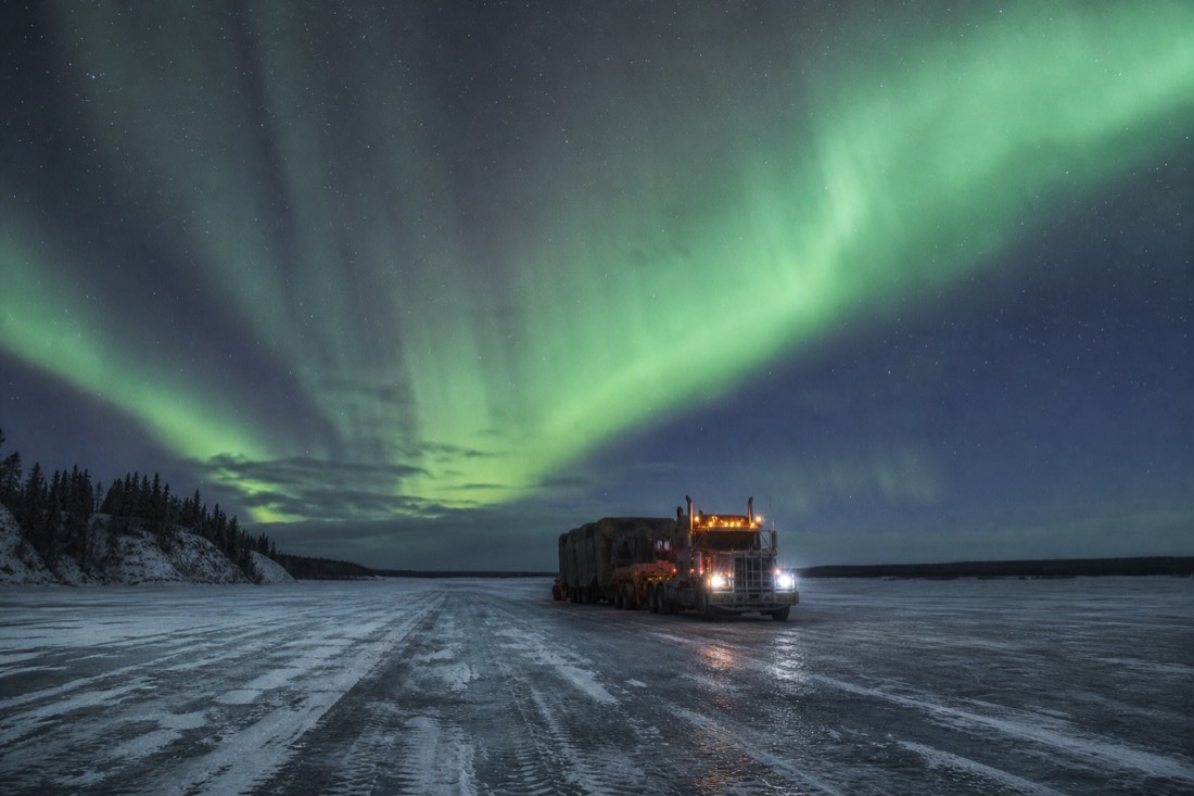 Heavy transport truck far out on a vast frozen lake under a pale winter sky
