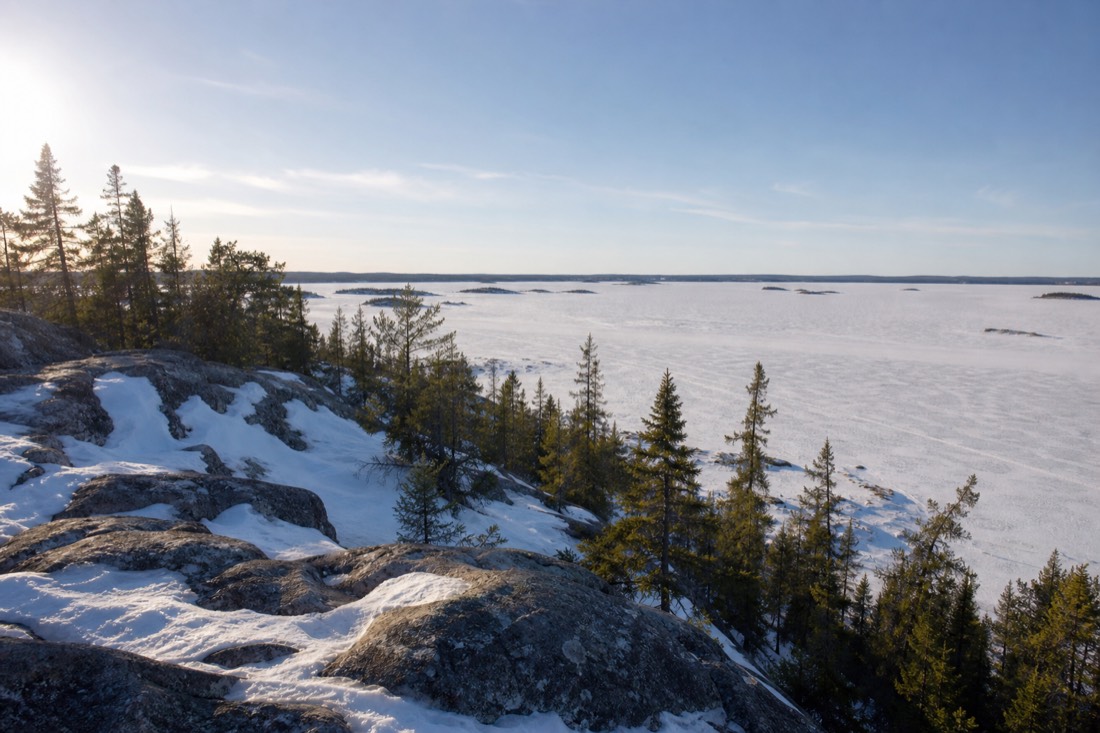 Bright April afternoon in Yellowknife with wet snowbanks, bare rock showing through, and long light across the frozen bay