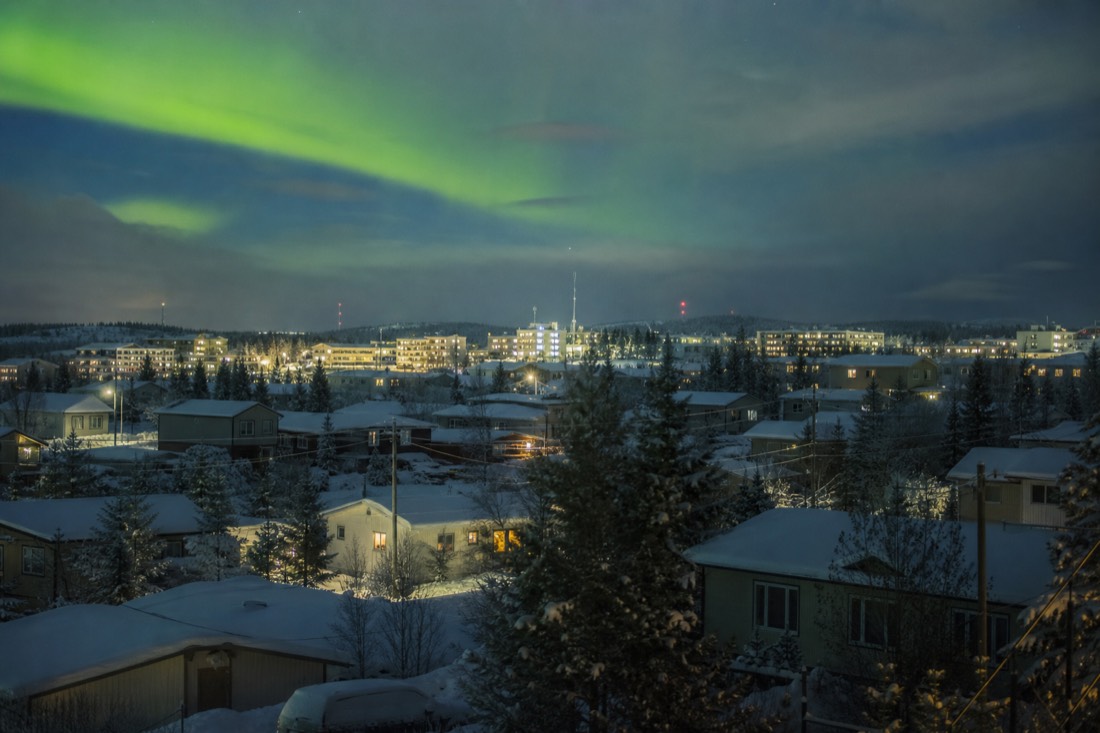 Twilight over snow-covered Yellowknife rooftops in December with lights on in the windows in mid-afternoon