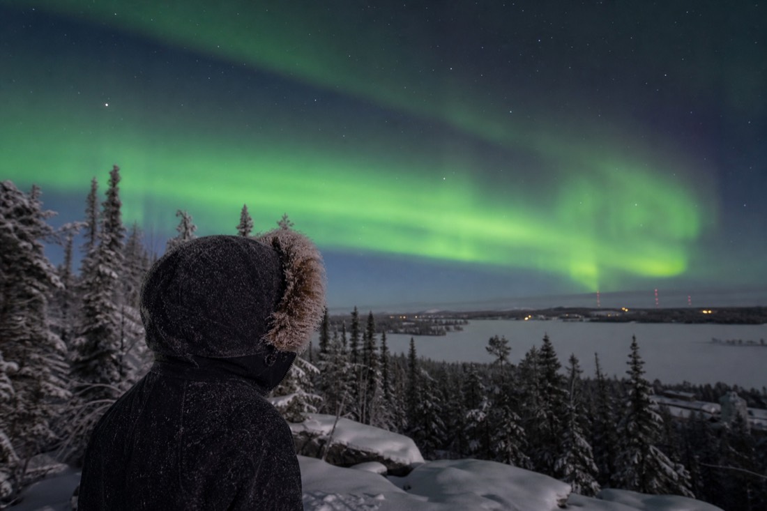 Frost-covered parka hood and eyelashes on a traveler standing outside on a December night in Yellowknife