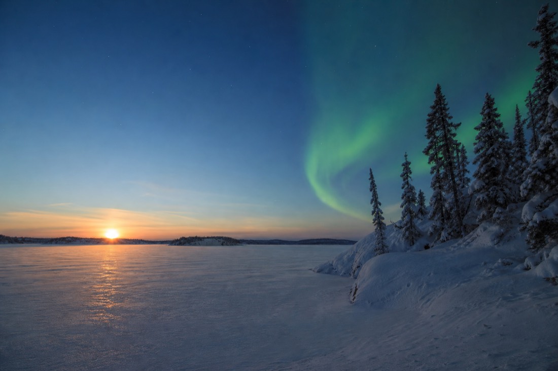 Low January sun sitting just above the horizon over snow-covered Yellowknife Bay in the middle of the afternoon