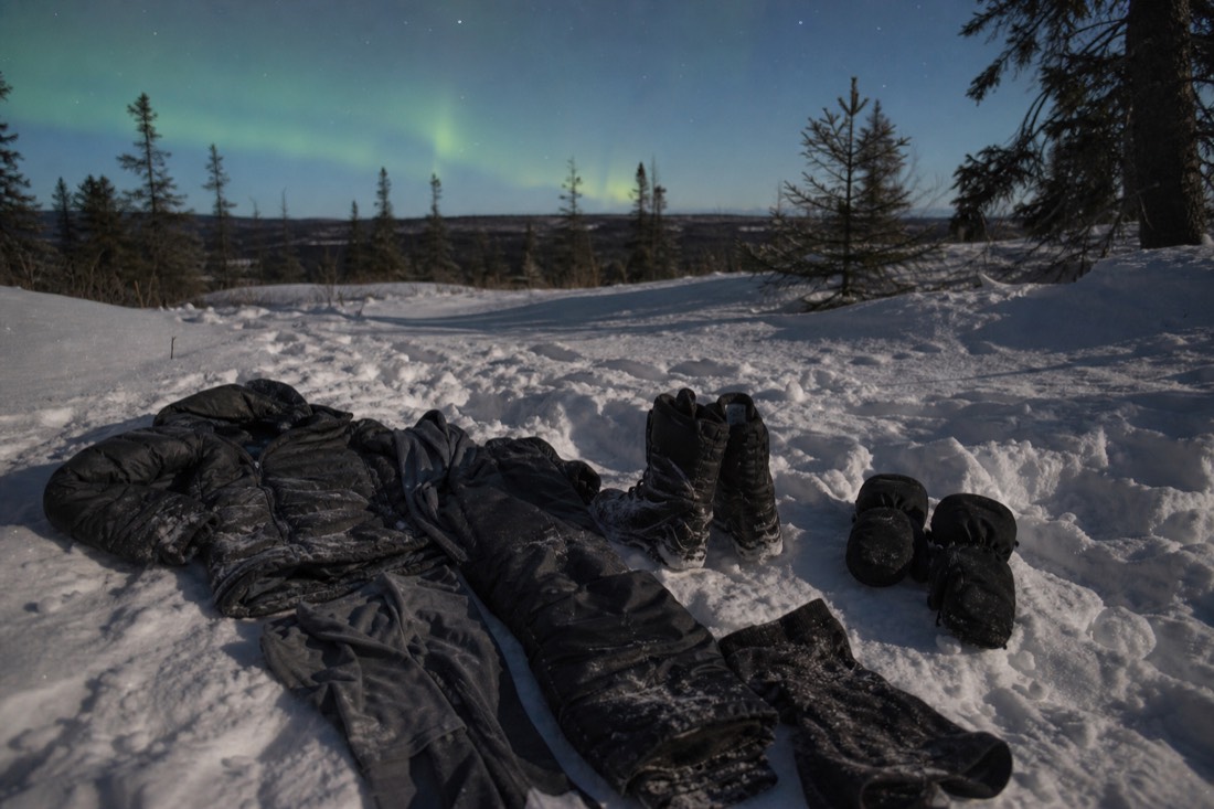 Winter clothing laid out for an aurora night: parka, insulated pants, boots, mitts and thermal layers