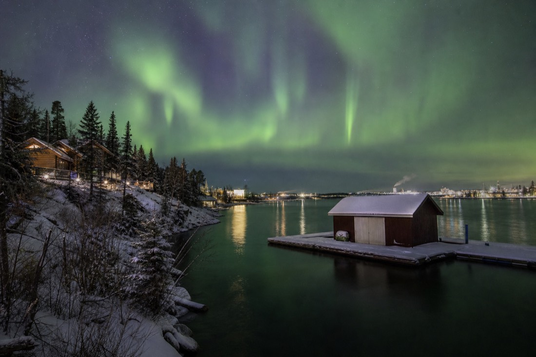 Log cabins and closed float plane dock in Old Town Yellowknife beside dark October water