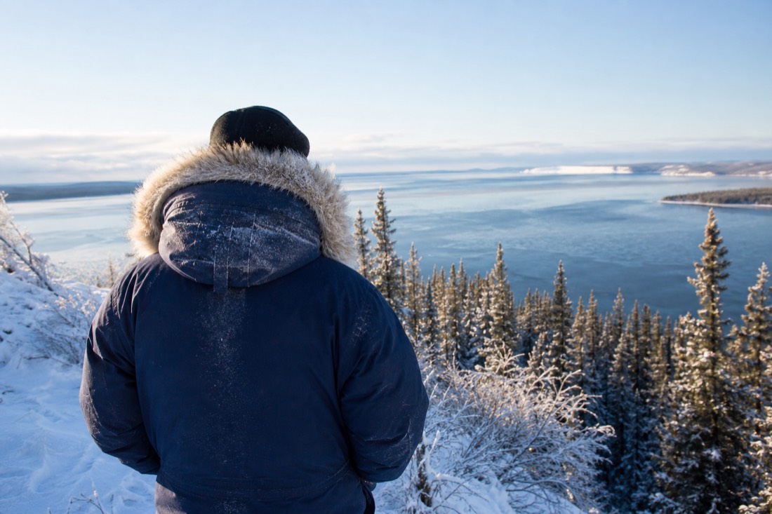Guide in a heavy parka with a frosted fur-lined hood smiling on a bright cold day near Great Slave Lake