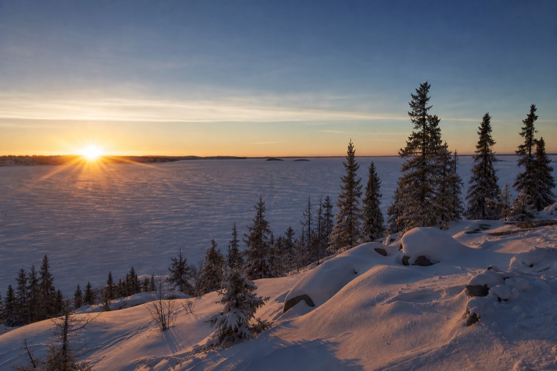 Low midwinter sun skimming the horizon over frozen Great Slave Lake at midday near Yellowknife