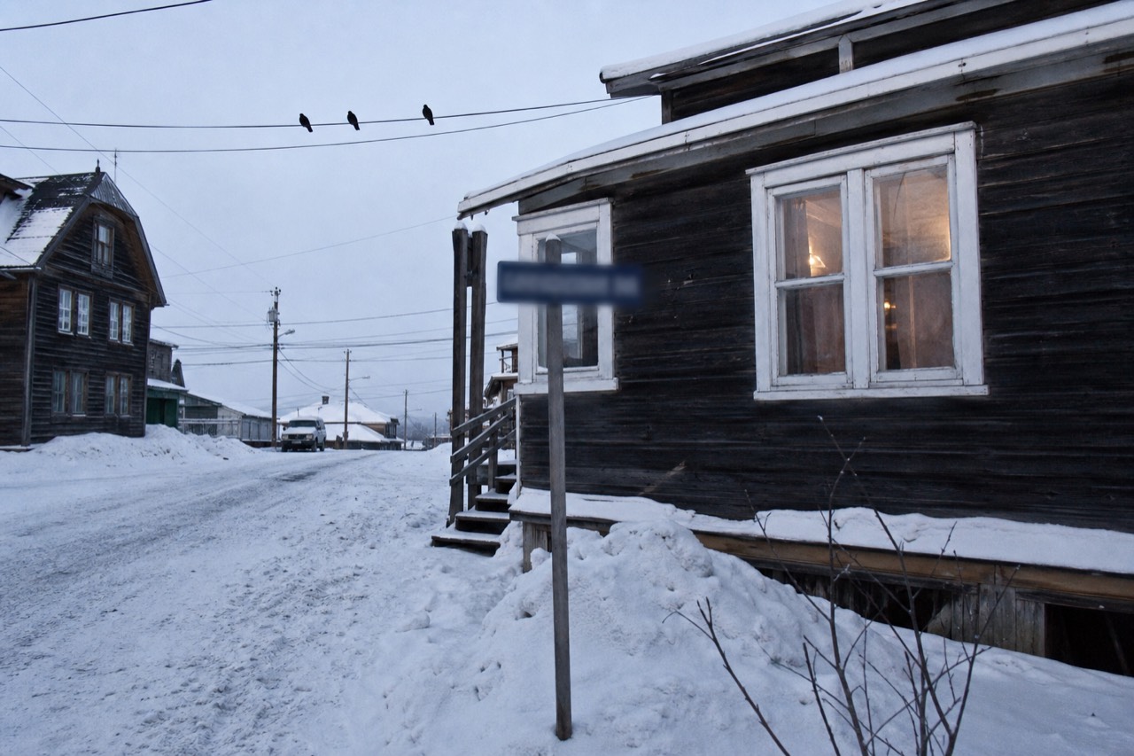 The snow-covered street corner of Ragged Ass Road in Old Town Yellowknife on a bright winter day
